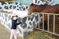 A girl watching horse drink water at cow farm.