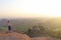 A girl is watching the sunset in Hampi. The girl stands on top of the mountain and looks into the distance. Meditation, harmony,