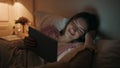 Girl watching tablet online at night closeup. Smiling woman resting bed enjoying Royalty Free Stock Photo