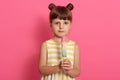 Girl with water ice cream posing isolated over pink background, wearing summer dress with white and yellow stripes, standing with Royalty Free Stock Photo