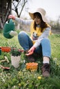 Girl watering planted flower while sitting in the yard