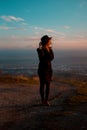 Girl waving her hat with her back facing the valley with mountains. aunset Royalty Free Stock Photo
