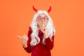 Girl wear devil horns and party glasses having long white hair wig pointing finger and keep a secret with hush gesture