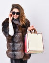 Girl wear sunglasses and furry coat shopping white background. Lady hold shopping bags. Discount and sale. Buy with