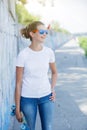 Girl wearing blank white t-shirt, jeans posing against rough street wall Royalty Free Stock Photo
