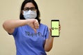 Girl wearing mask showing Ola app on her mobile phone screen showing thumbs down against yellow background.Its an aggregator
