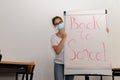 Girl wearing a medical mask in an empty classroom with back to school on whiteboard, new normal back to school Royalty Free Stock Photo