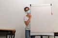 Girl wearing a medical mask standing behind a whiteboard in an emprty classroom, new normal, copy space Royalty Free Stock Photo