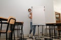 Girl wearing a medical mask standing behind a whiteboard in an emprty classroom, new normal, copy space Royalty Free Stock Photo