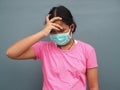 A girl wearing a protective mask With his hand on the temples Due to being sick