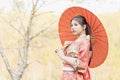 A girl wearing a red kimono and holding a red umbrella stands on a mountain in Kyoto Royalty Free Stock Photo