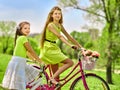 Girl wearing red polka dots dress rides bicycle into park. Royalty Free Stock Photo