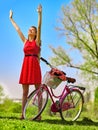 Girl wearing red polka dots dress rides bicycle into park. Royalty Free Stock Photo