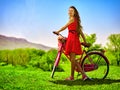 Girl wearing red polka dots dress rides bicycle into park. Royalty Free Stock Photo