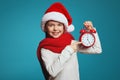 Girl wearing Santa hat and showing the time on the red alarm clock in hands Royalty Free Stock Photo