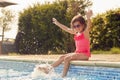 Girl Wearing Sunglasses Having Fun Splashing Sitting On Edge Of Swimming Pool On Summer Vacation Royalty Free Stock Photo