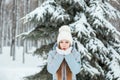 A Girl Wearing Warm Winter Clothes And Hat Blowing Snow In Winter Forest, horizontal Royalty Free Stock Photo