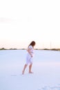 Girl wearing white dress walking barefoot on sand. Royalty Free Stock Photo