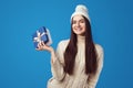 Girl wearing white oversize sweater and hat, holding present box for christmas Royalty Free Stock Photo