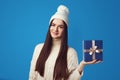 Girl wearing white oversize sweater and hat, holding present box for christmas Royalty Free Stock Photo