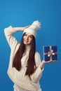 Girl wearing white oversize sweater and hat, holding present box for christmas Royalty Free Stock Photo