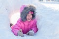 A girl wearing winter warm clothes - down jacket and fur hood enjoying play in snowdrifts. Happy child wintertime Royalty Free Stock Photo