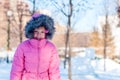 A girl wearing winter warm clothes - down jacket and fur hood enjoying sunny day in the park. Happy child wintertime Royalty Free Stock Photo