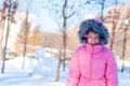 A girl wearing winter warm clothes - down jacket and fur hood enjoying sunny day in the park. Happy child wintertime Royalty Free Stock Photo