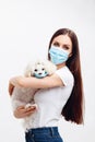 Girl wears disposable mask holds her puppy wears disposable mask too