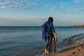 A girl in a wetsuit with flippers ih her hands and dry bag walking along the beach Royalty Free Stock Photo