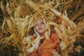 The girl in wheat lies in a dress and laughs. Golden spikelets of millet. Concept of unity with nature Royalty Free Stock Photo