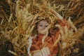 The girl in wheat lies in a dress and laughs. Golden spikelets of millet. Concept of unity with nature Royalty Free Stock Photo