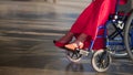 Girl in a wheelchair, in the frame of female legs in red shoes Royalty Free Stock Photo