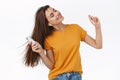 Girl whip her hair back and forth as enjoying awesome sound of wireless earphones, holding smartphone, close eyes Royalty Free Stock Photo