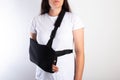 A girl on a white background with a black supporting medical bandage after a dislocation of the shoulder joint and a