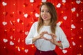 A girl in a white blouse shows a heart with her hands. Red background. Valentine`s day concept Royalty Free Stock Photo