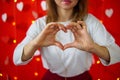 A girl in a white blouse shows a heart with her hands. Red background. Valentine`s day concept Royalty Free Stock Photo