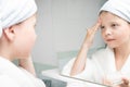 Girl in a white coat moisturizes her face with cream Royalty Free Stock Photo