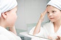 Girl in a white coat moisturizes her face with cream