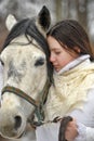 Girl in a white coat in winter with a horse