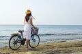 Girl in a dress with a bicycle on the seashore.