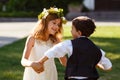 A girl in a white dress is dancing with a boy in a fashionable suit.