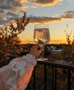 Girl in a white dress with a glass of white wine against the background of the sunset. Royalty Free Stock Photo