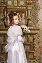 Girl in a white dress with a hairstyle in retro style with flowers in her hands Royalty Free Stock Photo