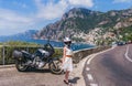 Girl in a white dress and a helmet posing. Touristic motorcycle on a background of the sea. Southern coast of Italy. Hot sunny day Royalty Free Stock Photo