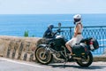 A girl in a white dress and helmet sits on a motorcycle. Touristic bike on the background of the sea. The coast of Italy. Hot Royalty Free Stock Photo