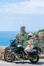 A girl in a white dress and helmet sits on a motorcycle. Touristic bike on the background of the sea. Vertical photo. Hot sunny Royalty Free Stock Photo