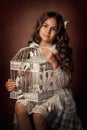 A girl in a white dress holds a blue decor cage in her hands. White butterflies sit in the cage and on the cage. Royalty Free Stock Photo