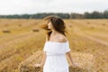 A girl in a white dress and with long hair turns her head, the hair develops on her fac