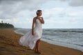 Girl in a white dress meets the sunset on the beach of the tropical ocean